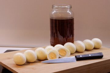 Row of boiled eggs for pickling and by glass jar of brown vinegar
