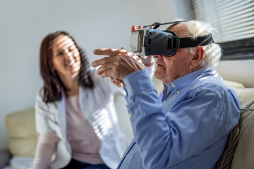 Fototapeta premium Senior man using a virtual reality headset while a nurse sitting in the background at a nursing home.