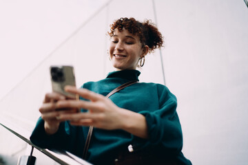Woman surprised and elated while reading smartphone screen, captured with mouth open and expressive reaction. Moment highlights emotional response to digital content. © BullRun