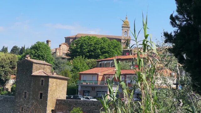 Charming view of cathedral Holy Saviour church and historical buildings surrounded by nature in the serene town of Montalcino, Tuscany