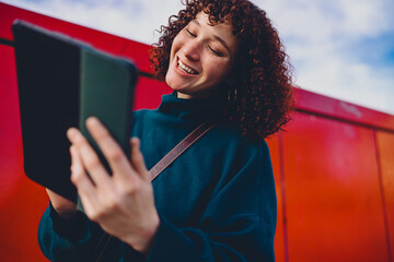Close-up of smiling woman holding stylus to chin, gazing down at tablet. Captures intimate moment of inspiration, digital interaction, and creative thought in mobile design workflow. © BullRun