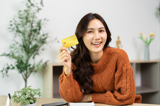 Financial Empowerment. A young woman proudly displaying her credit card while smiling.