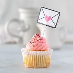 A single homemade vanilla cupcake with rose frosting for Valentine's Day.