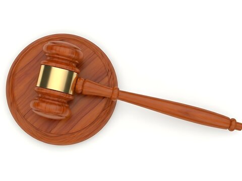 Close-up of a brown wooden judge's hammer and striking block, representing authority, order, and the judicial branch.