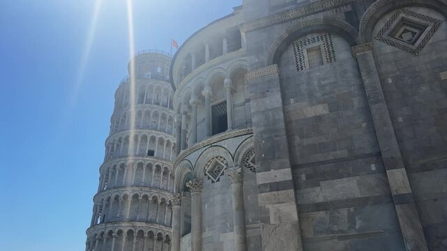 Leaning Tower of Pisa and cathedral facade backlit by summer sun with clear blue sky