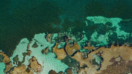 Aerial view of turquoise waters meet rugged, sun-kissed rocks, creating a mesmerizing dance of color and texture, Rottnest Island, Western Australia, Australia.