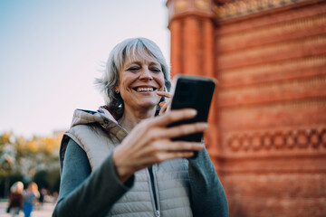 Woman checks her smartphone with concentrated expression while walking in city daylight — capturing focused engagement and personal tech use in everyday life.