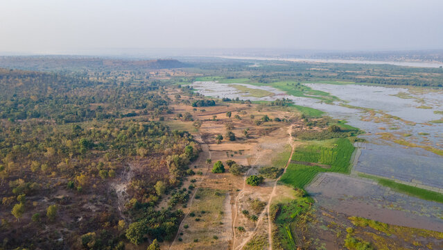 Aerial view of a landscape where water meets land with a contrast between lush greenery and dry earth, Essan, Niger, Nigeria.