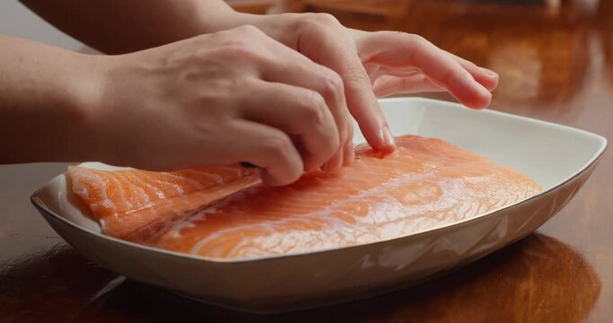 Preparing the salmon: Remove the bones from the fillet with a piercer. Season the fresh salmon fillet on a wooden table with sea salt and add refined sugar.