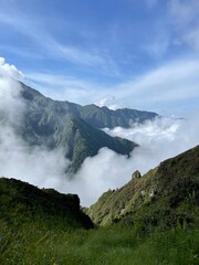 Fototapeta premium Mountain view with fog and clouds in a green landscape during daytime near a hiking path