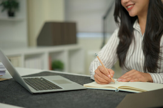 Cropped shot businesswoman hand working with writing on notebook