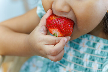 Little girl eating fresh strawberry - Close up of child biting fruit.