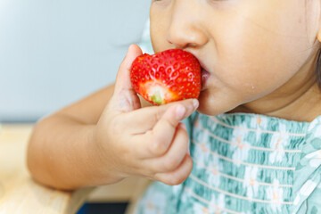 Little girl eating fresh strawberry - Close up of child biting fruit.
