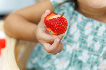 Little girl eating fresh strawberry - Close up of child biting fruit.