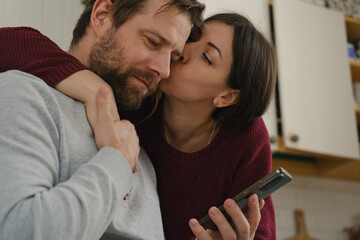 Loving mature couple using mobile phone. Husband and wife hugging, holding hands and looking at the...