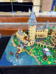 Obraz premium Side view of a massive custom LEGO Hogwarts Castle diorama featuring the Great Hall, students in boats on a blue brick water surface, and the Whomping Willow with a car: 06.10.2024-Ljubljana, Slovenia