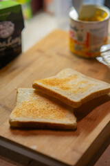 Two Lightly Toasted Slices of White Bread on a Wooden Cutting Board for Breakfast Preparation