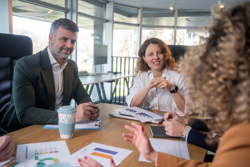 Casual meeting of smiling diverse business team analyzing financial data