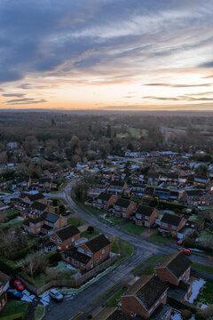 Aerial view of rooftops and roads nestled amongst trees, with a soft sunrise casting a warm glow, Hartley Wintney, England, United Kingdom.