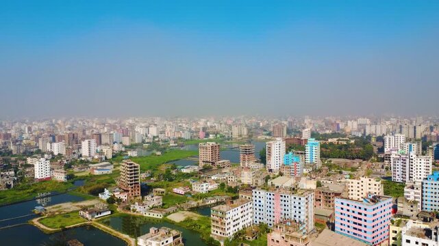 An aerial Drone view of a densely populated city in Dhaka Matuail, featuring numerous residential buildings, wetlands, and a hazy sky.
