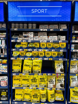 Sports nutrition display in a bright store aisle featuring protein shakes and supplements