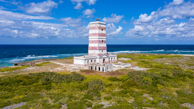 Aerial view of the striking red and white lighthouse standing tall against the blue sea and sky, Ilha de Goa, Nampula, Mozambique.