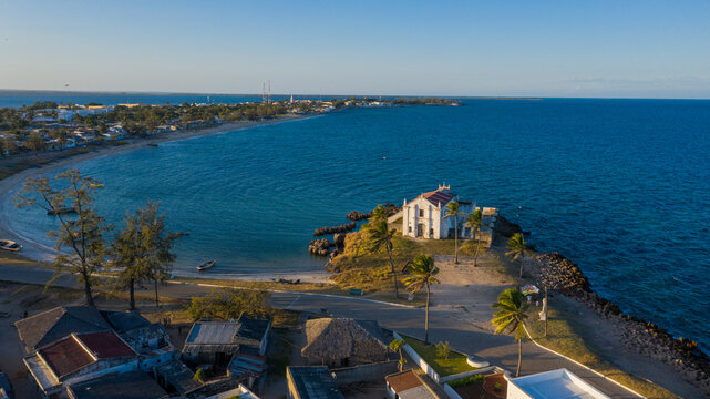 Aerial view of the Chapel of Nossa Senhora de Baluarte standing starkly against the turquoise sea, a beacon of history and faith, Ilha de Mocambique, Nampula, Mozambique.