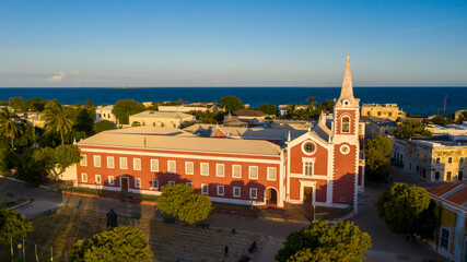 Aerial view of the striking red and white church steeple piercing the skyline against the backdrop of the turquoise ocean, Ilha de Mocambique, Nampula, Mozambique.