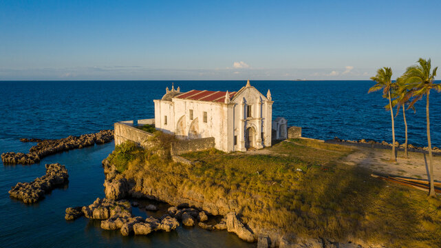 Aerial view of the Chapel of Nossa Senhora de Baluarte standing proudly on a small island with the Indian Ocean's waves crashing against the rocky shores, Ilha de Mocambique, Nampula, Mozambique.