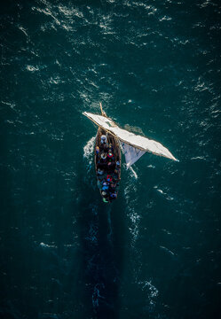 Aerial view of a traditional dhow sailing on the turquoise waters of the Indian Ocean, its white sail contrasting with the deep blue, Ilha de Mocambique, Nampula, Mozambique.