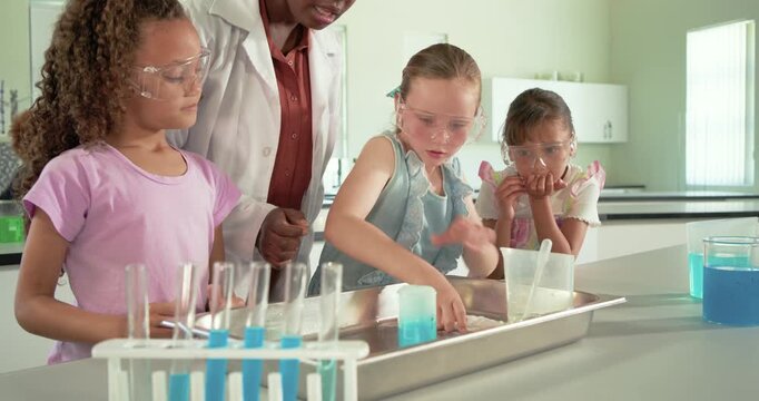 Female teen students with science teacher scooping, pouring into blue beaker at school lab for demo