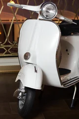 White scooter parked indoors on a dark floor with a blurred ornate background © yasidakbar
