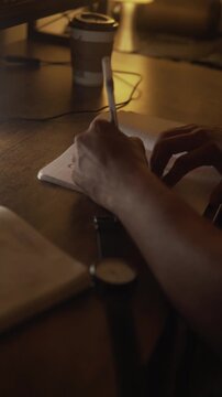 Person writing goals in a notebook at night