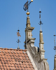 Old church roof with decorative spires and weather vanes under clear blue sky in a historic town