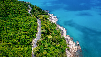 Aerial view of road between coconut palm tree and great ocean at daytime in Nakhon Si Thammarat, Thailand