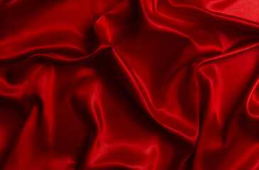 The luxurious and elegant bright red satin fabric draped in beautiful, flowing waves.