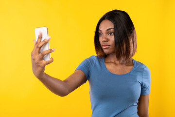 Biometric Verification Application. Serious African American Lady Making Selfie On Smartphone Unlocking Phone Via Face ID App Standing On Yellow Background. Studio Shot