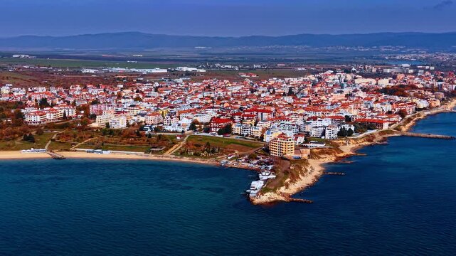 Dense urban landscape with colorful buildings. Drone footage over the blue waterscape of the Black Sea in Bulgaria.