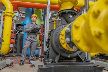 Asian engineer wearing glasses working in the boiler room,maintenance checking technical data of heating system equipment,Thailand people