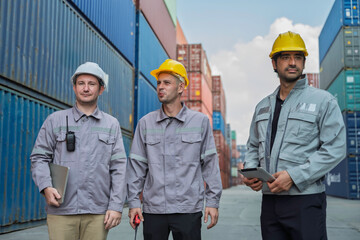 Team of professional logistic engineers inspecting shipping containers at a busy cargo port. Men pointing and discussing global export business plans using a digital tablet technology.