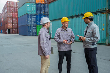 Team of professional logistic engineers inspecting shipping containers at a busy cargo port. Men pointing and discussing global export business plans using a digital tablet technology.