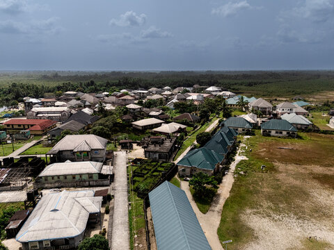Aerial view of rooftops glinting under the diffused sunlight, nestled amidst lush greenery, creating a vibrant tapestry of life and nature, Soku, Rivers, Nigeria.