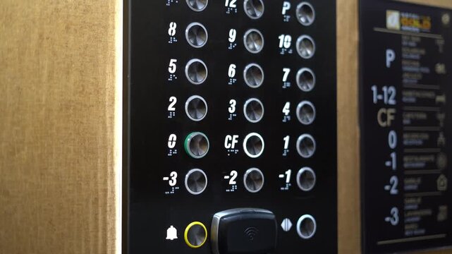 Hand pressing floor button on modern elevator control panel