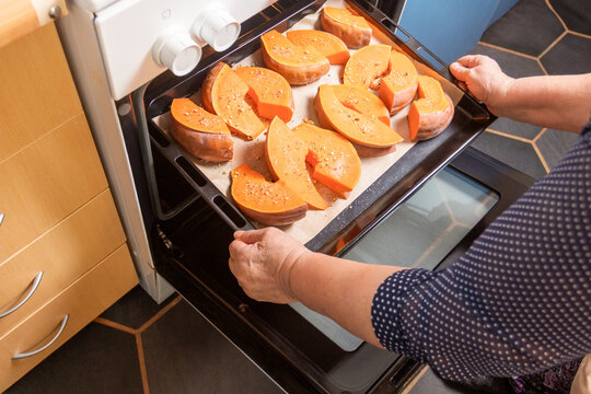 Woman baking pumpkin slices at home kitchen