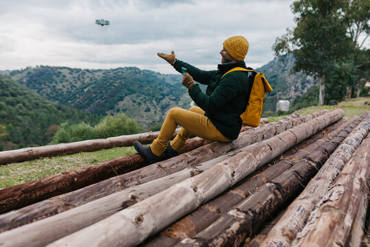 Man with backpack controlling drone in nature