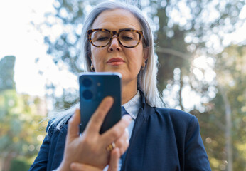 A Confident Woman is Engaged While Using Her Smartphone in a Beautiful Park Setting