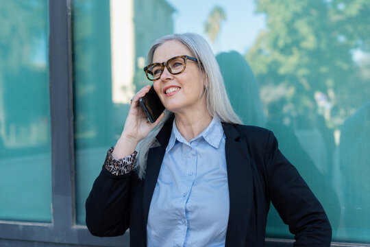 A Confident Businesswoman Engaged in a Phone Conversation in a Vibrant Urban Setting