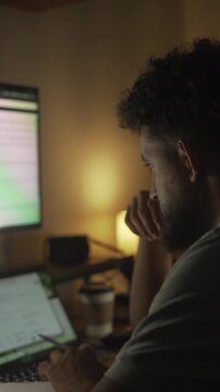 Stressed man working late at night on laptop in a dimly lit room