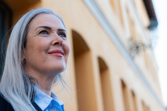 Smiling businesswoman looking up at building with hope and confidence