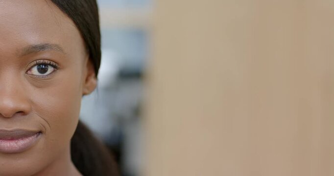African American woman holding gaze softening into laughing smile at work by wood panel, copy space